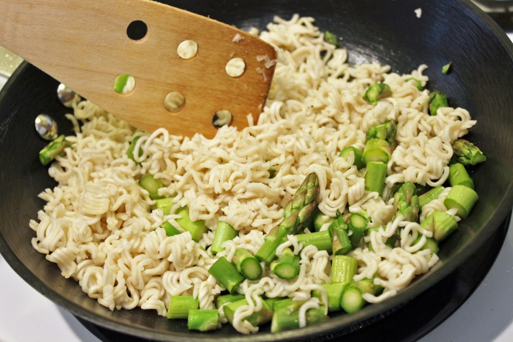 Frying instant noodles with asparagus in wok.