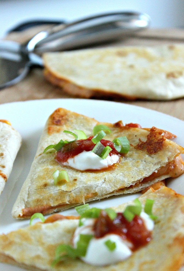 Cheese and Refried Bean Quesadillas topped with sour cream, salsa and green onions