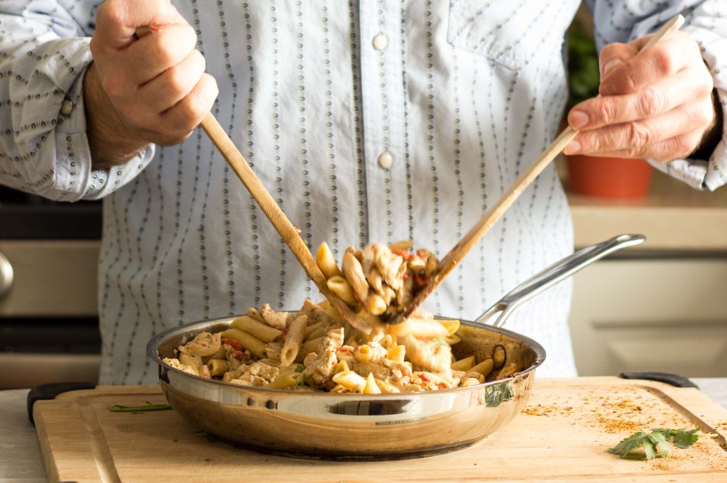 Tossing together cajun chicken and pasta with roasted red pepper cream sauce
