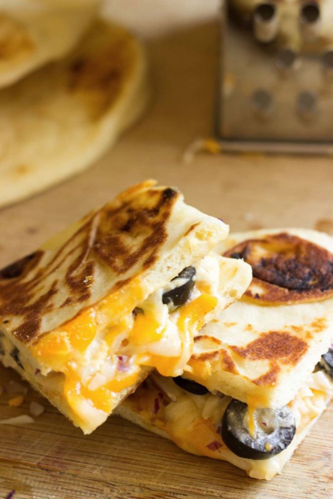 Naan bread and hummus grilled cheese sandwich with cheese grater and naan bread in the background