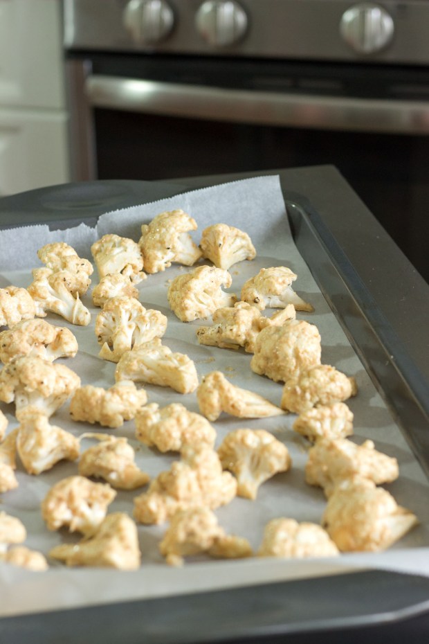 Coated cauliflower pieces on sheet pan ready for roasting